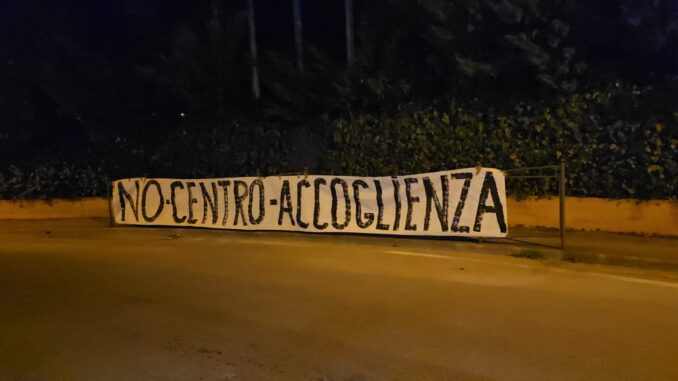 No centro accoglienza, uno striscione compare alla ex Villa, ma qualcuno lo ha strappato